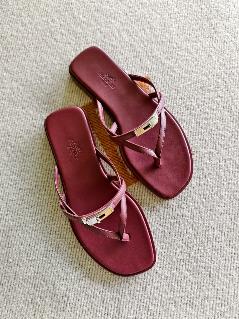 Pair of maroon sandals on a textured surface