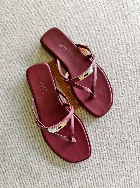 Pair of maroon sandals on a textured surface